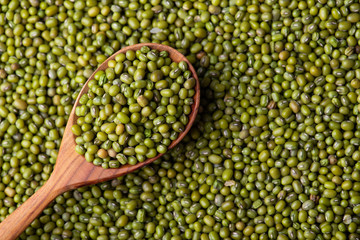 Scattered mung bean. Eco spoon. Mung bean, green moong in a wooden spoon, on black metallic vintage background. Copy space. Black background. 