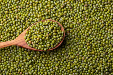 Scattered mung bean. Eco spoon. Mung bean, green moong in a wooden spoon, on black metallic vintage background. Copy space. Black background. 