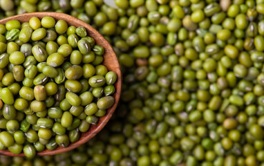 Scattered mung bean. Eco spoon. Mung bean, green moong in a wooden spoon, on black metallic vintage background. Copy space. Black background. 