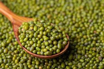 Scattered mung bean. Eco spoon. Mung bean, green moong in a wooden spoon, on black metallic vintage background. Copy space. Black background. 