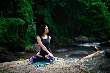 Yoga practice and meditation in nature. Woman practicing near river