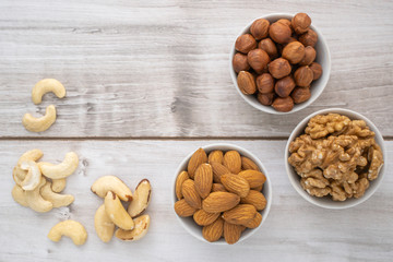 Different nuts in white bowls on wood table