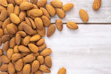 Scattered almond seeds on wooden table, stock photo.