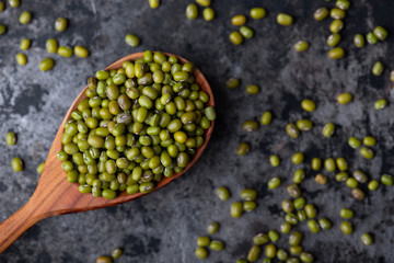 Mung bean, green moong in a wooden spoon, on black metallic vintage background. Copy space. Black...