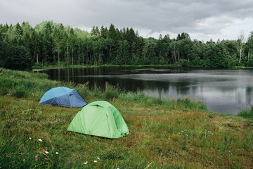 Two tourist tents on the shore of the beautiful lake on a summer day