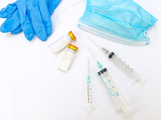 Medical syringe, antibiotic ampoule, gloves and a protective mask on a white background