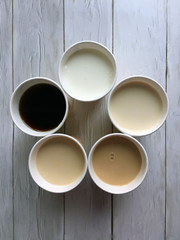 Five cups of coffee with milk close-up on a white wooden background with space for copying. Flat lay
