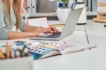 Woman with nice manicure is working on computer at creative studio.