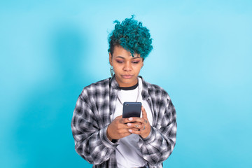 african american girl or woman with mobile phone or smartphone isolated on blue background