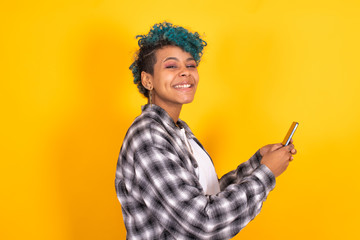 trendy young girl with mobile phone isolated on yellow background