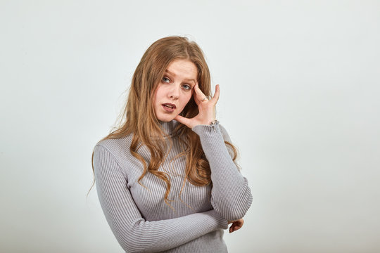 a young beautiful red haired woman in gray sweater makes decision with her head on hand gives birth to new idea