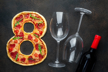 Dinner for two. Pizza in the form of 8, a bottle of wine and glasses for International Women's Day on March 8 on a stone background. March 8 celebration concept.