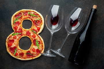 Dinner for two. Pizza in the form of 8, a bottle of wine and glasses for International Women's Day on March 8 on a stone background. March 8 celebration concept.