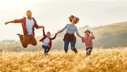 Happy family: mother, father, children son and daughter jumping on sunset.