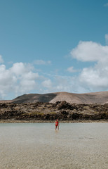 woman walking on beach and volcanic rocks