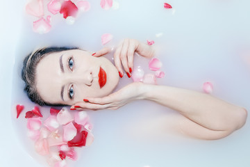 Obraz na płótnie Canvas Young sexy girl taking a milk bath with rose petals