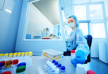 female scientist in a protective medical mask and rubber gloves makes PCR DNA tests in a modern chemical and bacteriological laboratory.