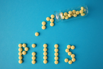 Yellow pills on blue background. Top view, medicine concept.