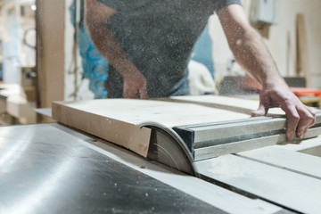 Caucasian man carpenter cutting wood with circular saw creating new furniture