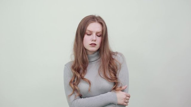 a young beautiful red haired woman in gray sweater looks stylish and confident clasps her hands