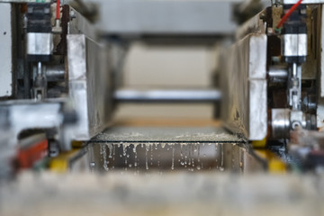 Polishing glass panes with water in glass factory. Special industrial equipment with conveyor belt in the factory.