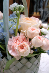 A bouquet of fresh flowers of roses, anemones and gartensium in a basket on a stone background.