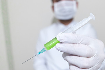 He is holding a coronavirus vaccine. The vaccine is green. On the left says corona virus vaccine found.