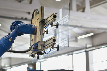 Robot in glass factory carrying glass pane