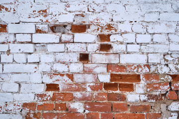 Background. The old red brick wall is partially painted with white paint.