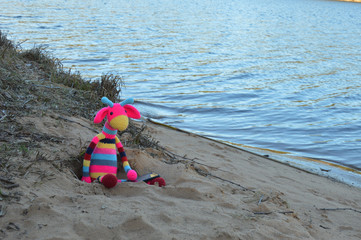 Amigurumi dolls at a photo shoot on the shore of a forest lake.