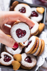 Homemade heart shaped linzer cookies with raspberry jam in woman hand. Close up. Baking with love concept.