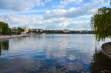 Obraz premium Aerial View of beautiful green city, the embankment and the blue lake against the blue sky and white clouds. Ternopil. Ukraine