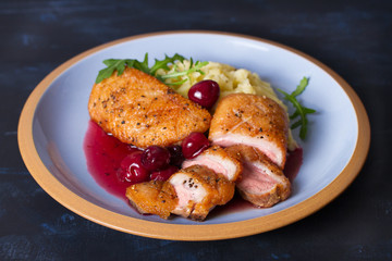 Duck breast fillet with cherry wine sauce and mashed potato on blue plate, dark background. horizontal image