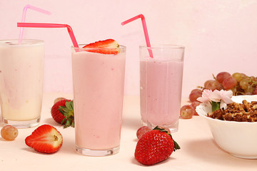 Strawberry and banana smoothies, granola, fresh berries and grapes on a pink sunny background. The concept of healthy and natural food. Useful breakfast,