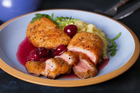 Duck breast fillet with cherry wine sauce and mashed potato on blue plate, dark background. horizontal image
