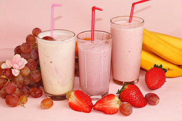 Strawberry and banana smoothies, granola, fresh berries and grapes on a pink sunny background. The concept of healthy and natural food. Useful breakfast,