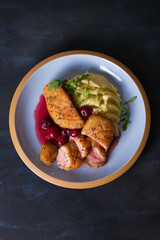 Duck breast fillet with cherry wine sauce and mashed potato on blue plate, dark background. Overhead Vertical image