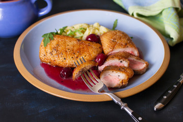 Duck breast fillet with cherry wine sauce and mashed potato on blue plate, dark background. horizontal image