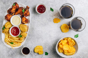 Table fof tasty snacks for beer prepared for watching sports on TV. Chicken. Chicken wings, chicken nuggets, french fries, chips and various sauces. Light gray background. Top view. Flat lay