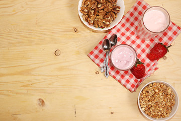 Strawberry smoothie or milkshake, granola, fresh berries on a wooden background. Concept of healthy and natural food. Healthy breakfast, rustic minimal style, top view