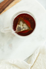 Black tea steeping in clear mug on marble