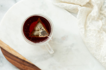 Black tea steeping in clear mug on marble