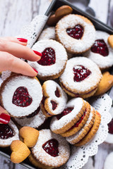 Homemade heart shaped linzer cookies with raspberry jam in woman hand. Close up. Baking with love concept.