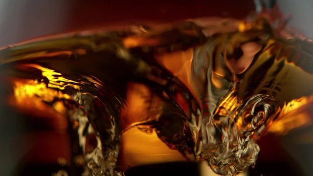 Super Slow Motion Detail Shot of Ice Drop into Glass with Whiskey at 1000fps.