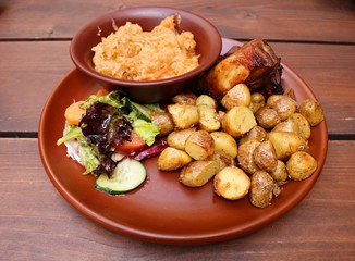 Grilled piece of pork, fried potatoes and stewed cabbage on a ceramic plate