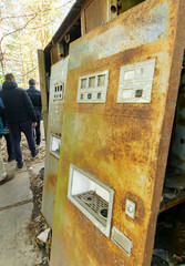 Old rusty radioactive soda mashine standing in Chernobyl nuclear disaster contaminated area.Tour group visitors on the background