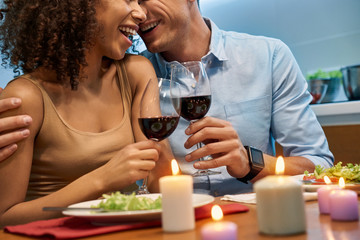 Young adult boyfriend and girlfriend with wine in hands enjoying romantic dinner