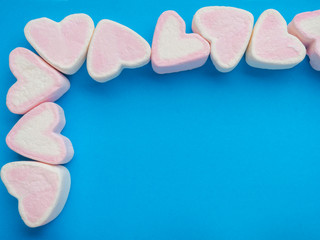 Pink marshmallow in heart shape stacked on trendy blue background with copy space. Sweet candy for love theme on Valentine concept. Pastel color dessert for background or wallpaper decor