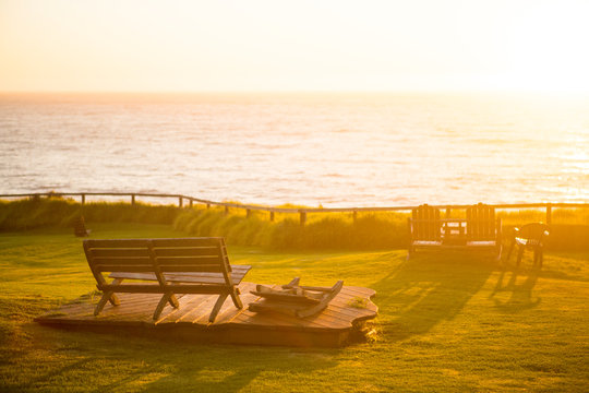 Wooden bench on cute platform overlooking the Pacific Ocean at sunset in Big Sur, California.