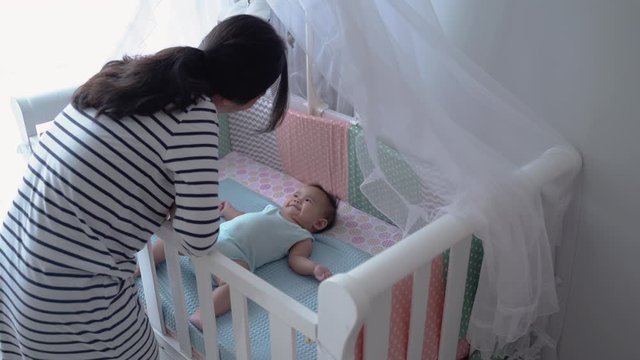 asian happy baby on the crib. mother and baby at home